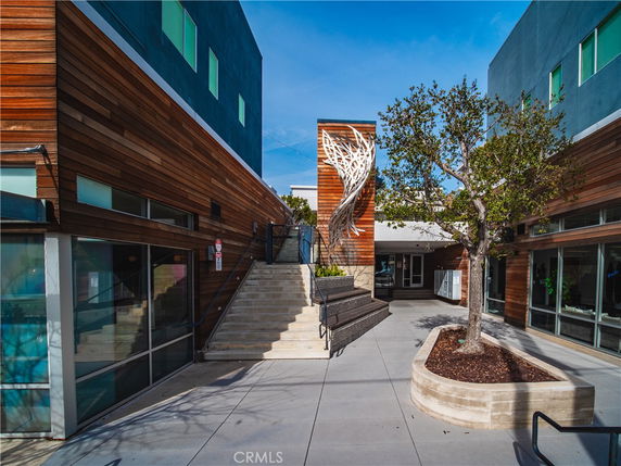 Front view of a modern building with wood and glass exterior elements and a decorative metal structure.