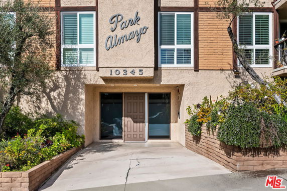 Front view of a building with multiple windows and decorative plants.