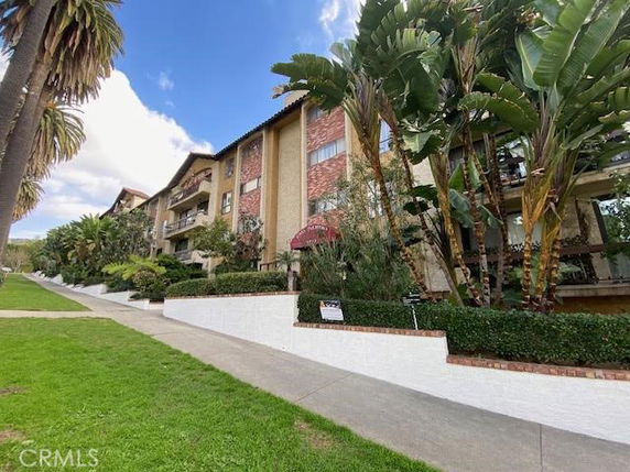 Front view of a multi-story residential building with balconies and landscaped surroundings.