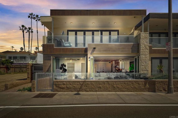Front view of a modern two-story house with large glass windows and balconies.