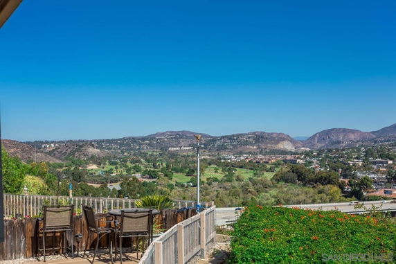Panoramic view from a patio showing a vast landscape with hills and a town in the distance.