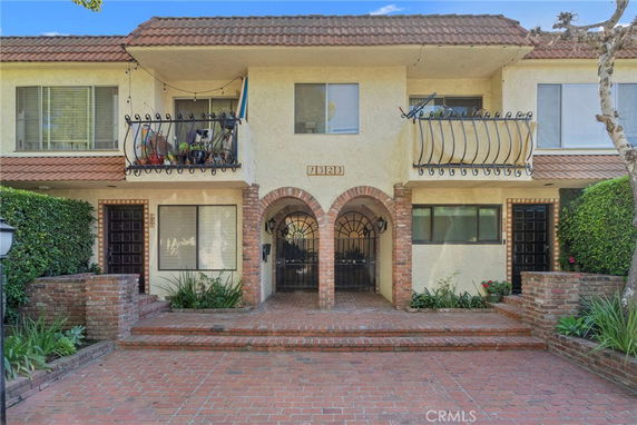 Front view of a two-story building with balconies and brick accents.