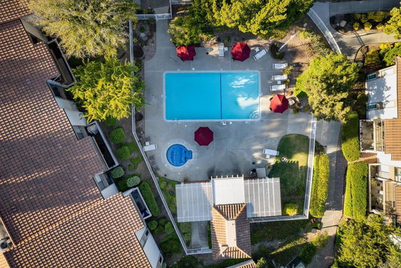 Aerial view of an outdoor swimming pool area surrounded by buildings and greenery.