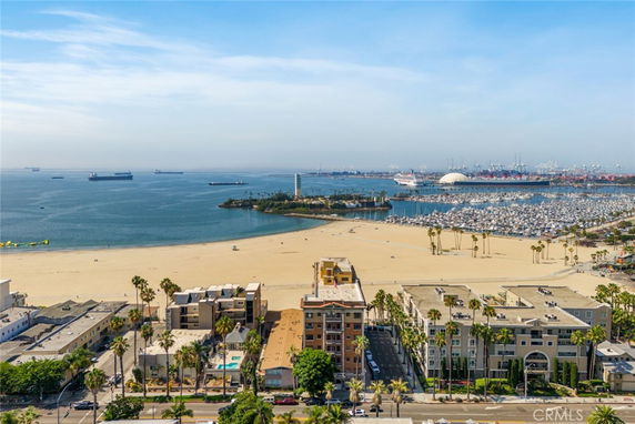 Panoramic view of a coastal area with buildings, beach, and marina.