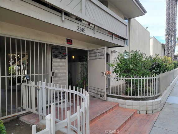 Front view of a two-story building with a gated entry and steps leading to the entrance.