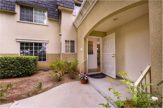 Entrance view of a house with an open door and garden area.