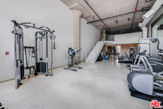 Indoor gym area with various exercise equipment and machines.
