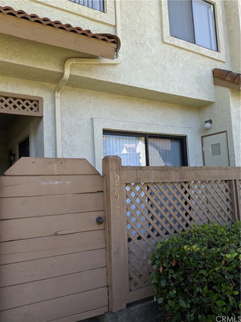 Front view of a two-story house with a wooden fence and a gated entrance.