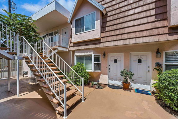 Front view of a two-story residential building with an external staircase leading to the upper level.