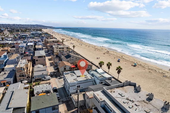 Aerial view of a coastal city with buildings near a sandy beach and ocean.