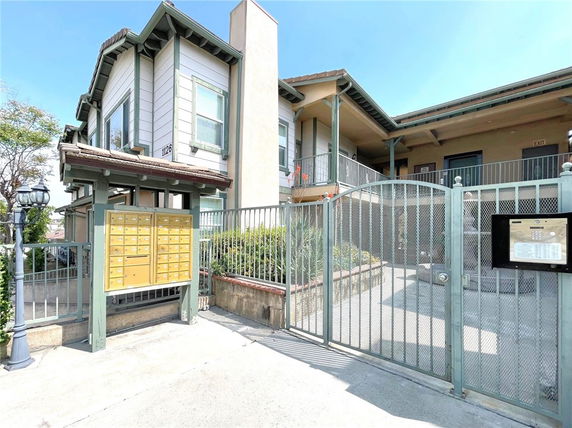 Front view of a two-story building with a gate and mailboxes.