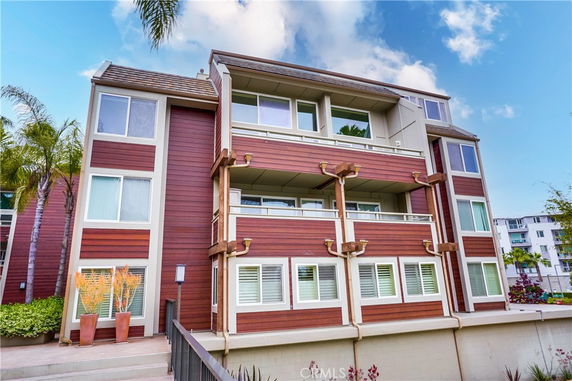 Front view of a multi-story residential building with wood paneling and balconies.