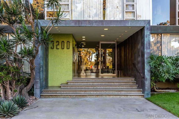 Front view of a building with steps leading to the entrance and a green tiled facade.