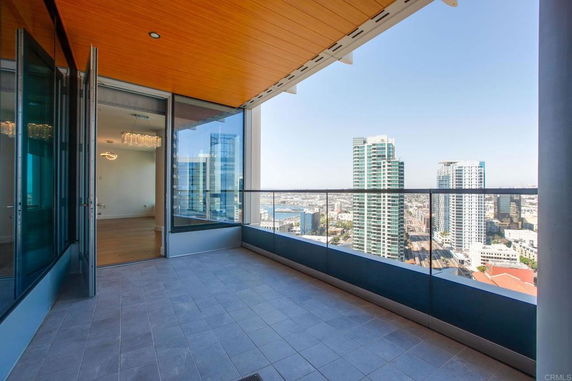 View from a balcony with glass railings overlooking a cityscape with multiple high-rise buildings.