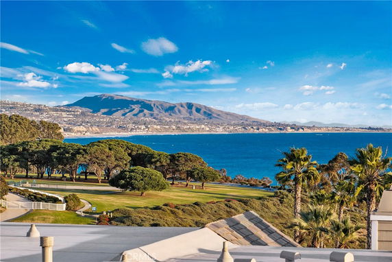 Wide-angle view of the ocean and surrounding landscape with hills and trees.