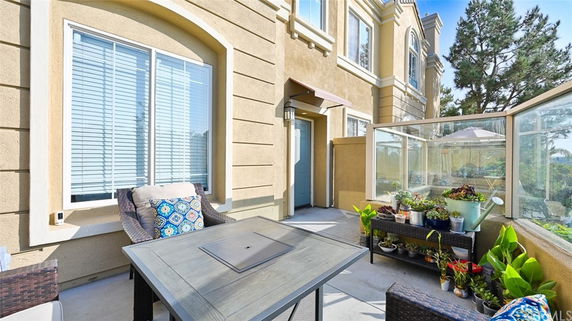 Front view of a house with a small patio area featuring outdoor seating and potted plants.