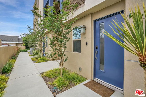 Front entrance of a modern building with blue door and sidewalk.
