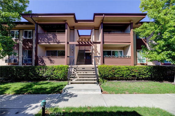 Front view of a two-story apartment building with an exterior staircase and balconies.