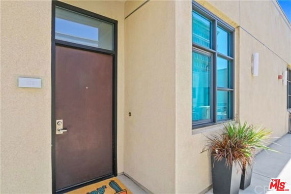 Front view of a modern building entrance with large windows and a brown door.