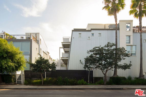 Front view of a modern multi-story building with balconies and vertical metal siding.