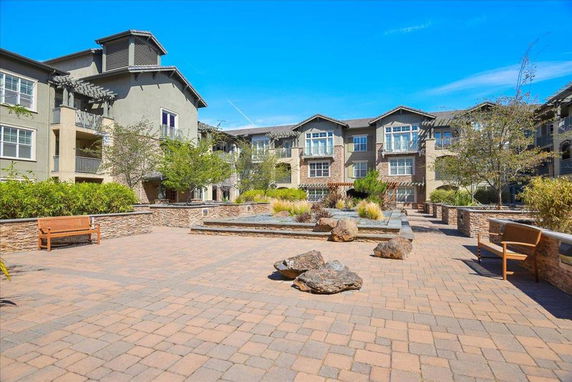 Front view of a multi-story apartment complex with landscaped courtyard.