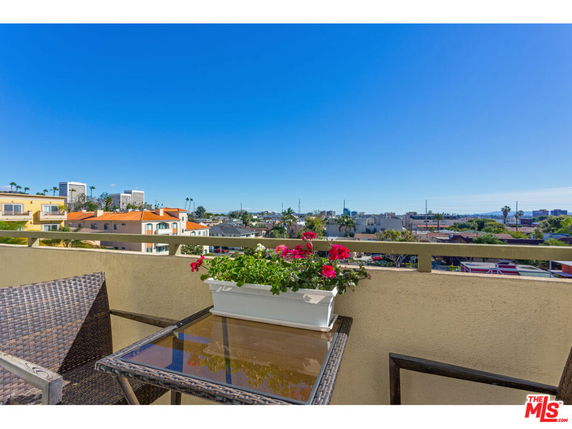 Panoramic view from a balcony showing the cityscape with buildings and clear blue sky.