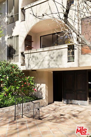 Front view of a building with a balcony and a covered entrance.