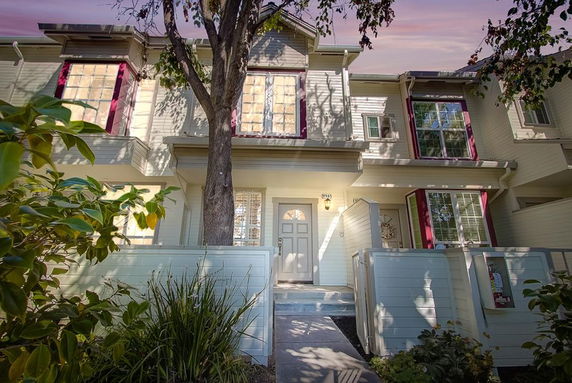 Front view of a two-story house with red window frames and a small front patio.