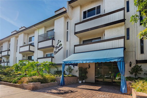 Front view of a multi-story residential building with balconies and an entrance canopy.