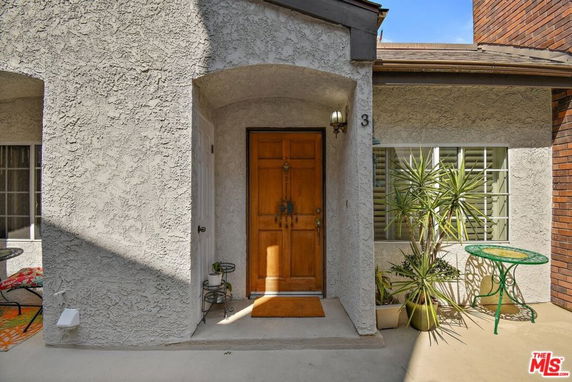Front view of a house entrance with a wooden door and surrounding windows.