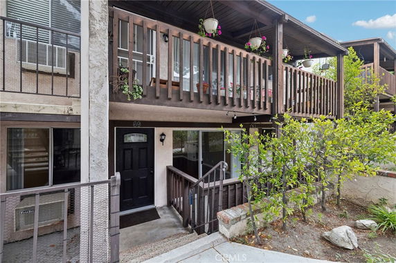 Front view of a two-story residential building with balconies and plants.