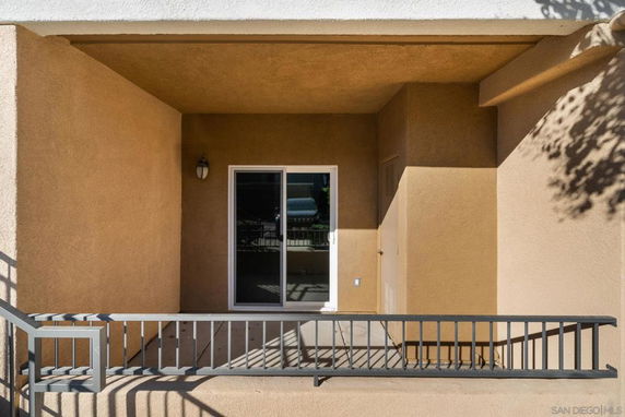 Front view of a building section with a small balcony and sliding glass door.