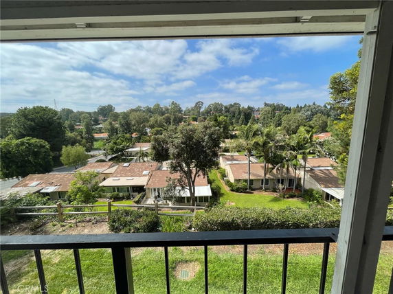 Panoramic view of houses and surrounding trees seen from a balcony.