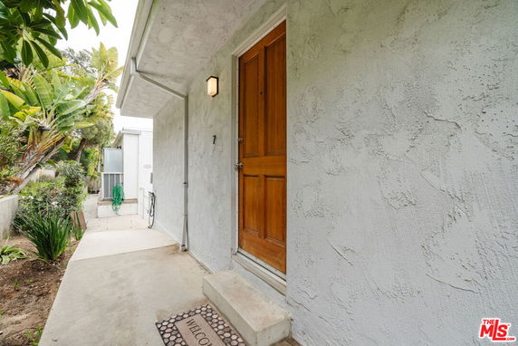 Front view of a house with a wooden door and textured wall.
