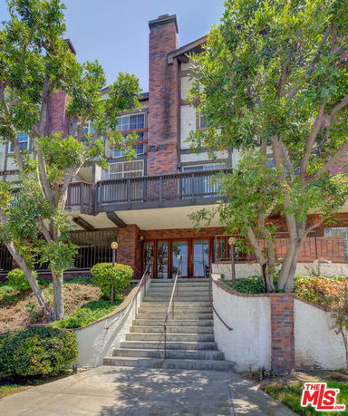 Front view of a multi-story brick residential building with staircase entrance.