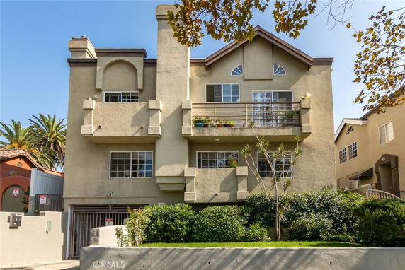 Front view of a multi-story apartment building with balconies and a garage entrance.
