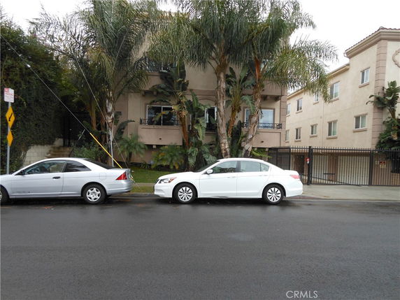 Front view of a multi-story residential building with palm trees.