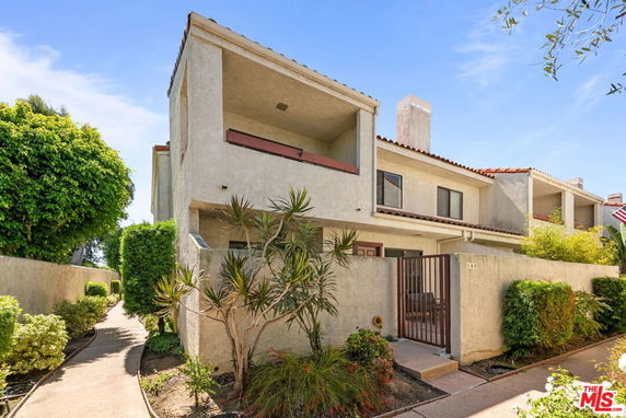 Front view of a two-story house with a balcony and a small garden area.