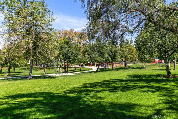 Green park area with pathways and a children's playground in the background.