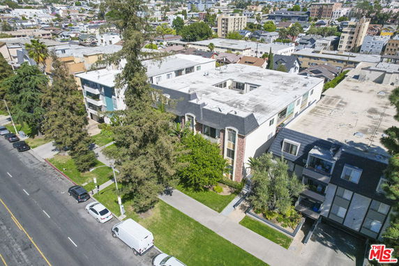 Aerial view of a multi-story residential building surrounded by trees and neighboring structures.