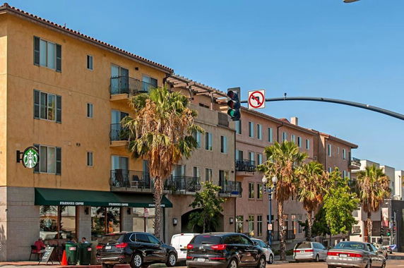 Front view of a multi-story building with retail shops on the ground floor and apartments above.