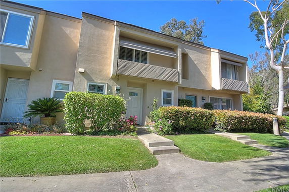 Front view of a two-story townhouse with a small porch and garden.