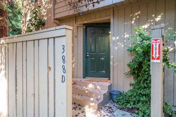 Front view of a house entrance with wooden siding and a green door.