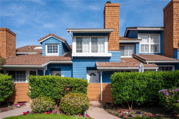 Front view of a two-story house with blue and brown siding, multiple windows, and a tiled roof.