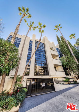 Front view of a multi-story building with large glass windows and gated entrance.
