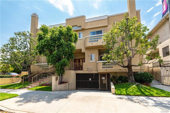Front view of a multi-story residential building with balconies and a gated entrance.