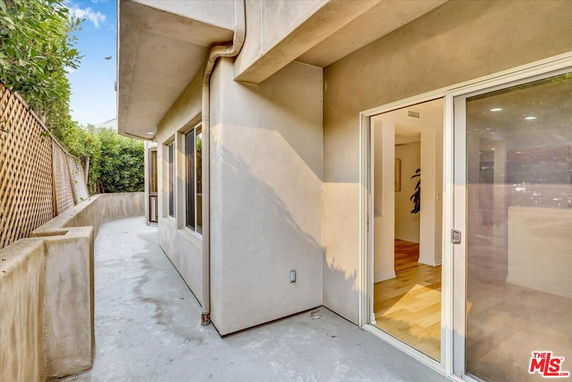 Concrete walkway leading to a sliding glass door on a modern building.