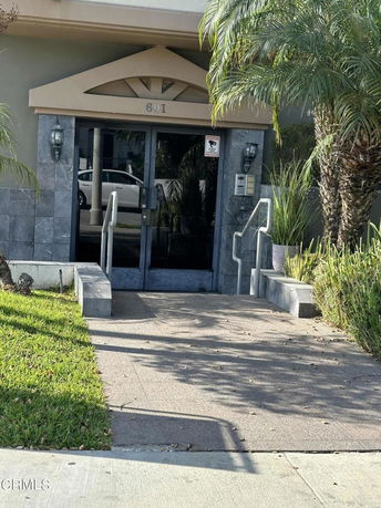 Front view of a building entrance with glass doors and steps leading up.