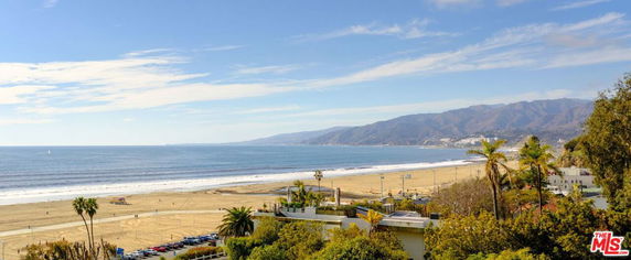 Panoramic view of a beach with mountains in the background and a clear blue sky.