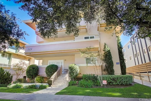Front view of a multi-story apartment building with a staircase leading to the entrance.